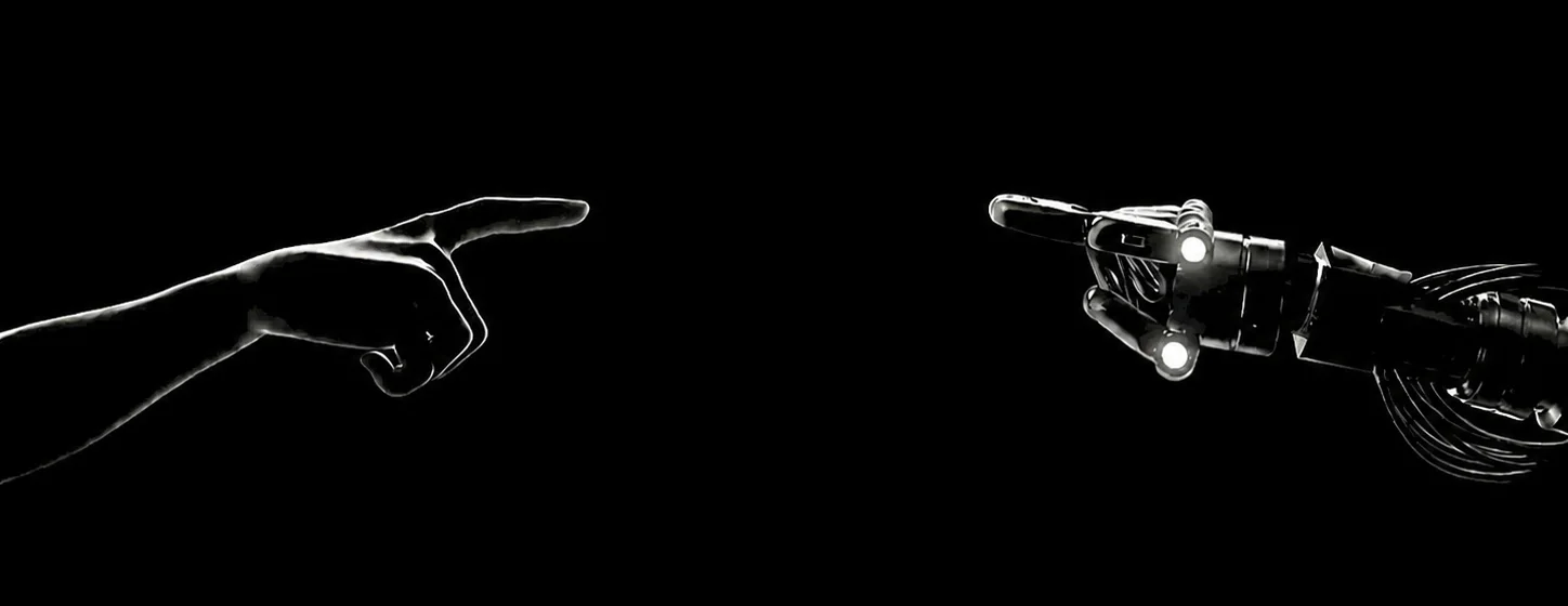 A human hand and a robot hand pointing toward each other across the dark